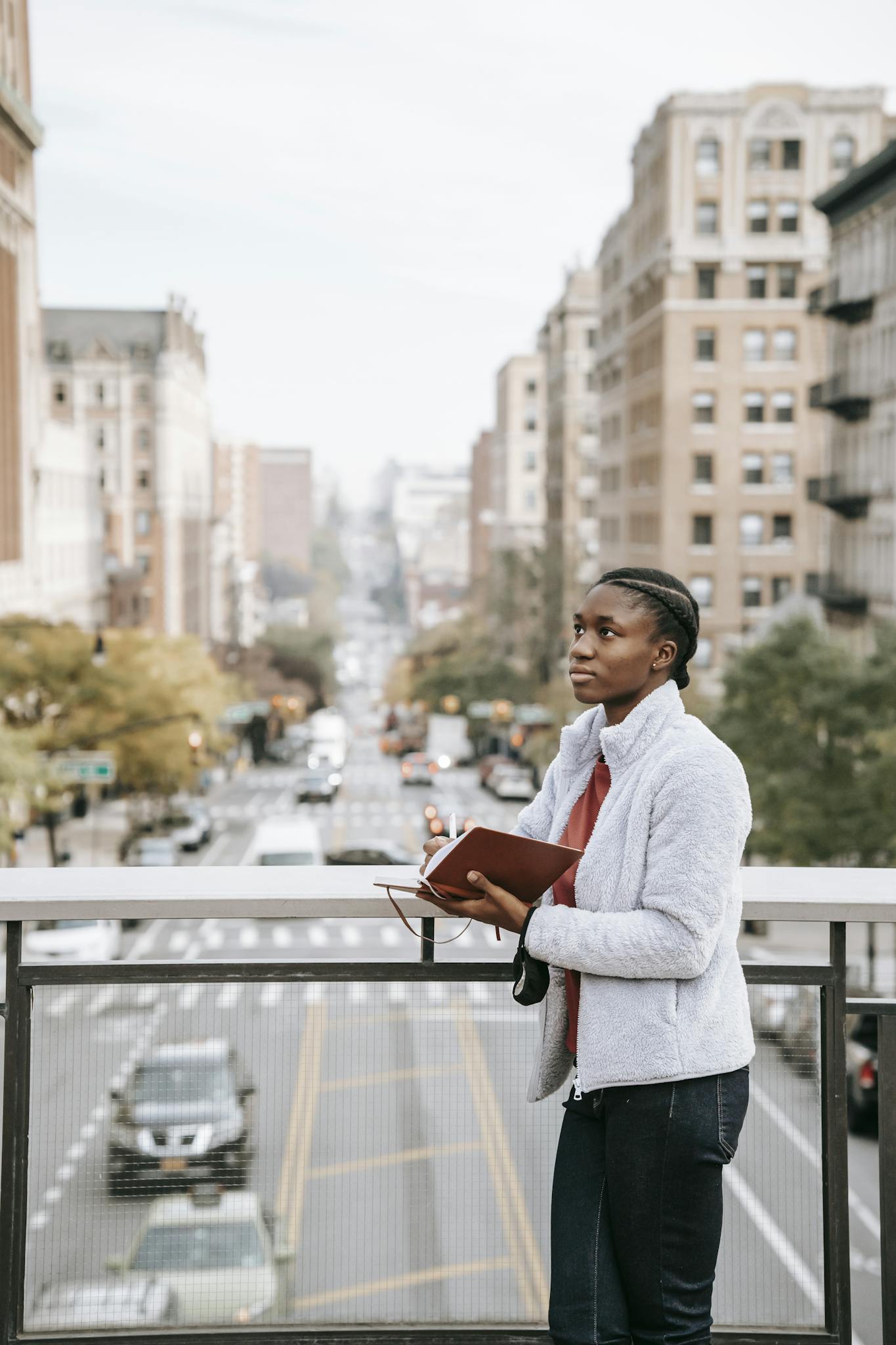 Contemplative ethnic student with journal on urban bridge